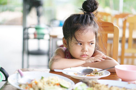 亚洲儿童可爱或小女孩厌食症或悲伤无聊的食物或无聊背景图片