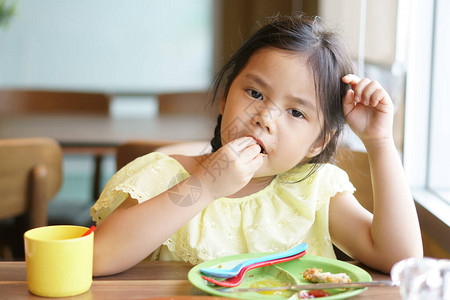 饥饿的亚洲儿童或小女孩喜欢用手吃食物图片