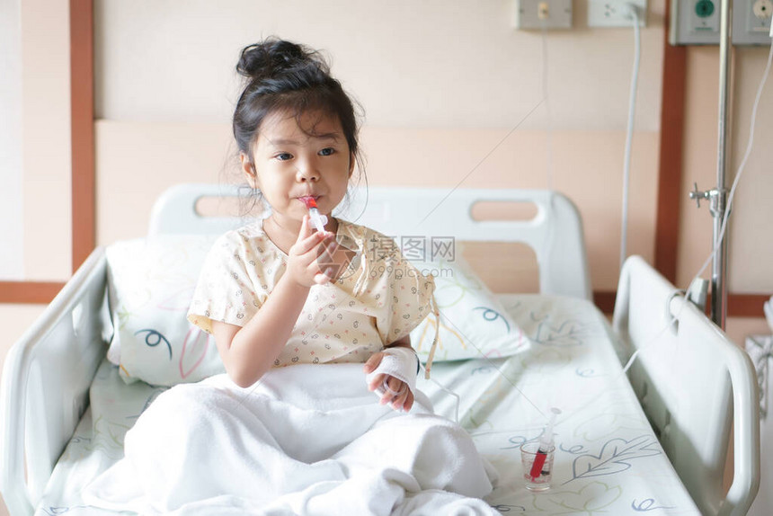 亚洲儿童可爱或小女孩流感病患者在病房床上用盐水注射泵吃或服用甜红药或水药图片