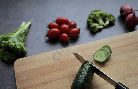 灰色桌上的切板上的新鲜蔬菜番茄生菜图片