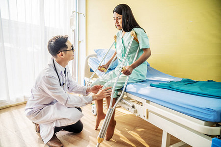亚洲男医生或物理治疗师检查膝关节事故后腿部或膝关节受伤的女患者图片