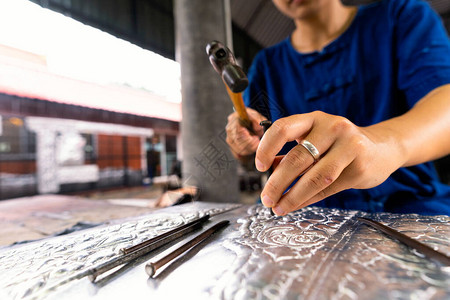 切割银器的女人的手泰国工匠正在制作银器工匠将复杂的图画雕刻成用于图片