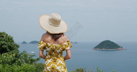 女人戴草帽在乡间看海景图片
