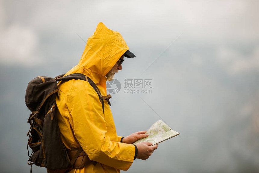 中年男子穿雨衣和背包旅行者图片