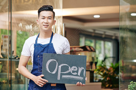 正面的亚洲青年男子站在咖啡厅入口处图片