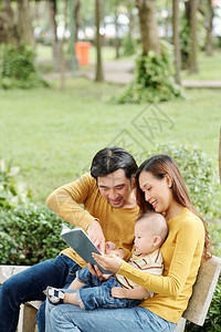 快乐的年轻父母在公园陪着小儿子图片
