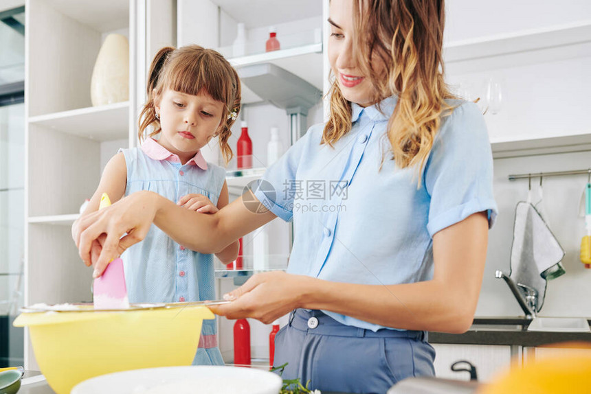 母亲和小女儿在大塑料碗中混合图片