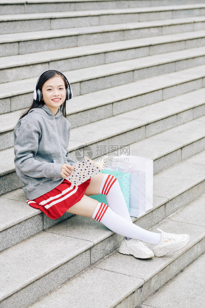 欢笑快乐的亚洲女孩在购物阅读书和听音乐后图片
