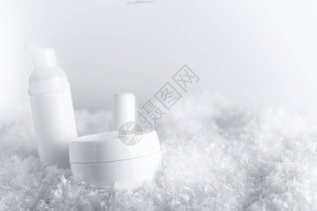白色蓬松雪地上的化妆品容器图片