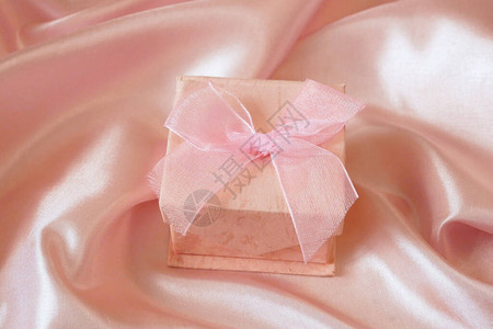 粉红丝绸背景的礼物盒图片