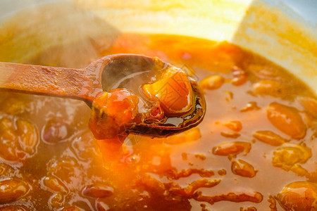 有杏子或桃果酱的碗木勺里的热果酱排水高清图片