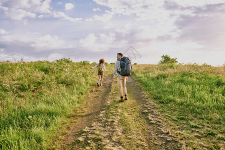 年轻女徒步旅行者背着包在乡间小路上奔跑的后视图图片