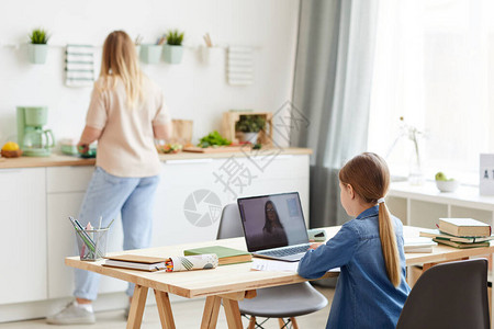 小女孩在与导师或老师的在线课程中使用笔记本电脑的后视图肖像图片