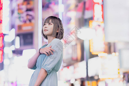 年轻女人在夜里在东京闪亮的城背景图片