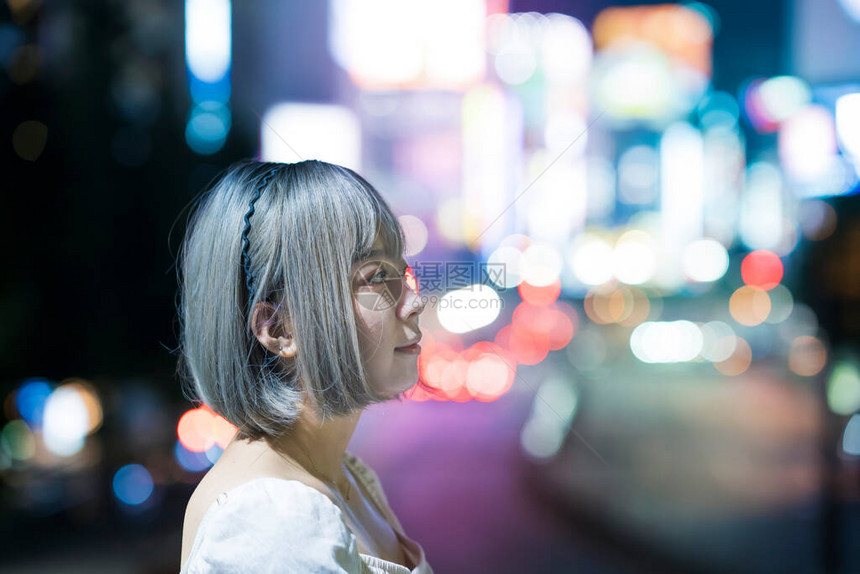 年轻女人在夜里在东京闪亮的城图片