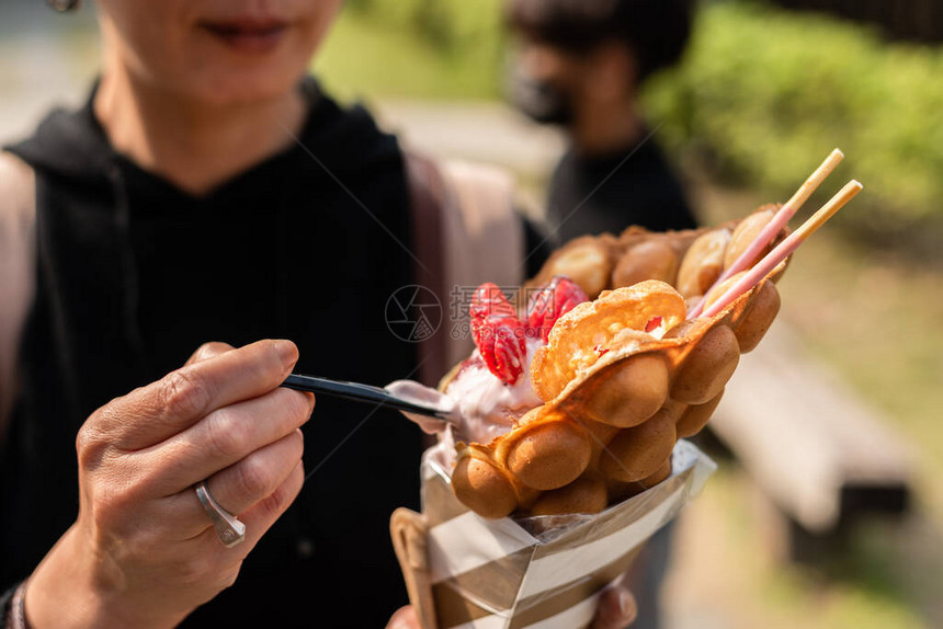 女人在街上吃草莓华夫冰淇淋图片