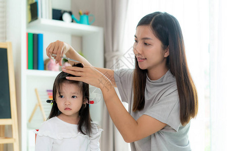亚洲母亲在家为女儿理发图片