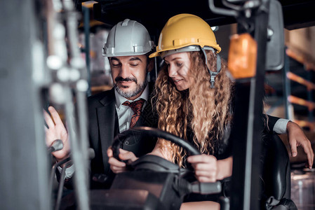 工程师驾驶叉车的女工和戴着安全帽的商人站在货物仓库货物旁图片