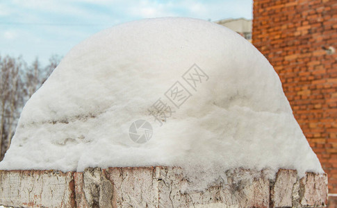 旧砖栅栏上一大片雪堆的特写高清图片