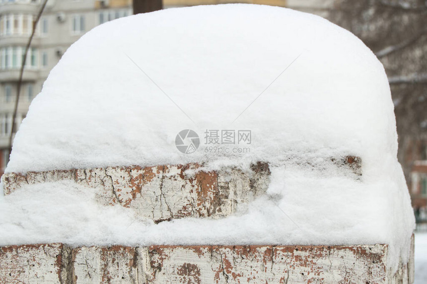 旧砖栅栏上一大片雪堆的特写图片
