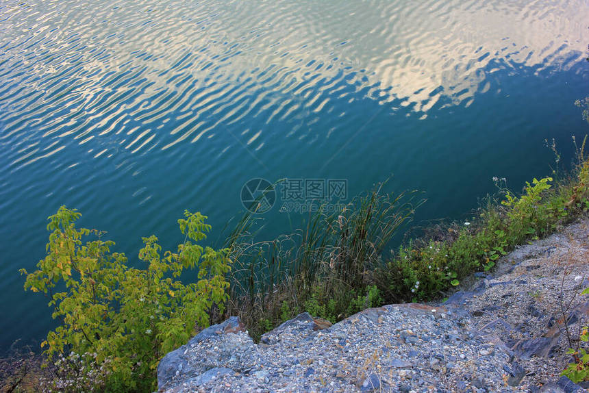 夏季的高山湖泊用氡水淹没旧花岗岩采石场的全景与石块绿树和干净图片