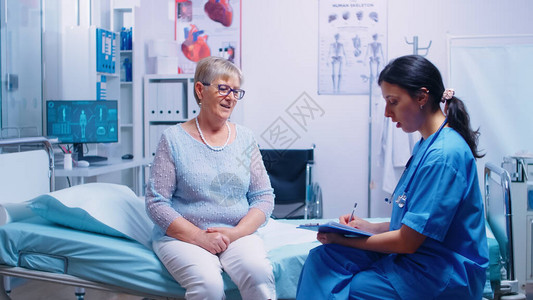 高级退休妇女在现代医院与护士讨论图片