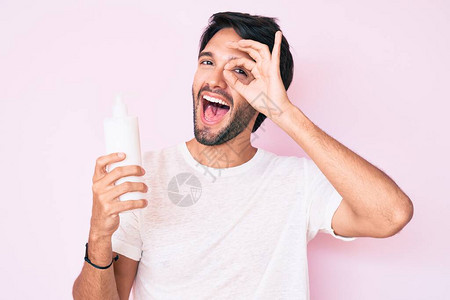 帅气的西班牙裔男子拿着化妆品保湿面霜微笑着开心地做着好手势图片