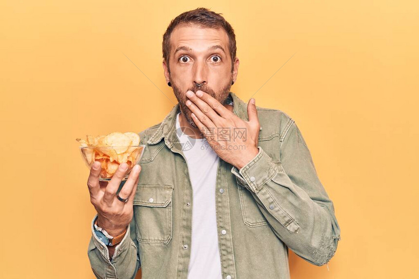 年轻英俊男子拿着土豆薯片手把嘴盖上图片