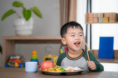 亚洲学生在教室里用学前班准备的食物托盘吃午餐图片