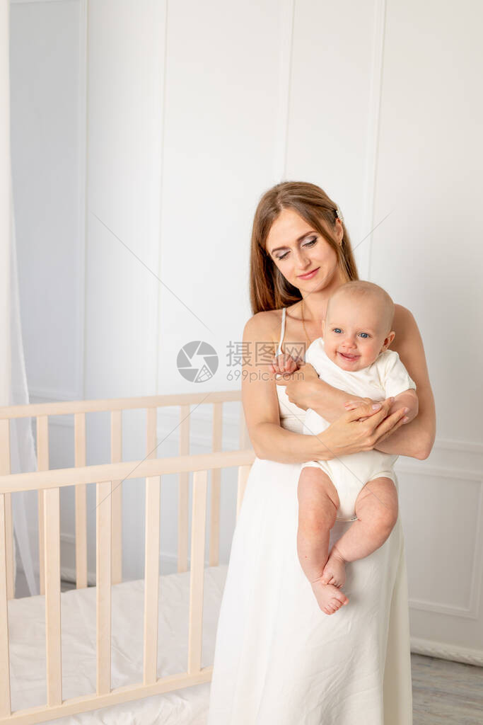年轻漂亮的母亲在托儿所里抱着女儿6个月图片