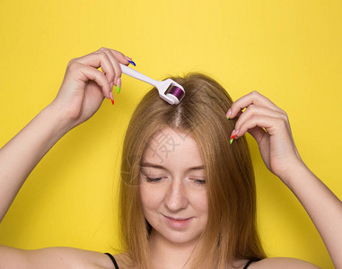 黄色背景的女孩与mesoroller头发和头皮的中胚层疗法美容头图片