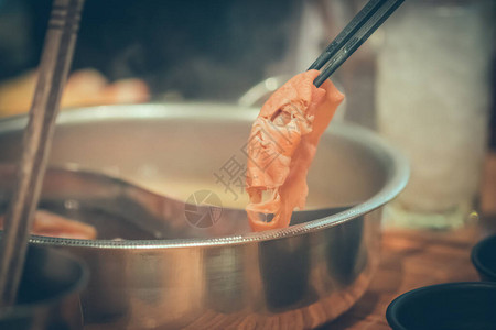 手持猪肉在热锅上用筷子和图片