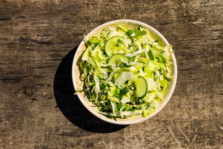 春食素沙拉配有卷心菜黄瓜绿洋葱和木背景图片