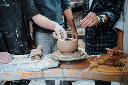 朋友们在陶工轮上处理粘土制作手工陶罐陶艺课图片