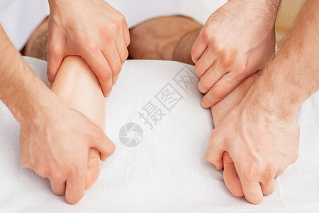 两只按摩器的手在温泉足部治疗期间正对图片