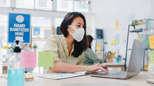 亚洲女企业家在新常态下戴着医用口罩进行社会疏离图片