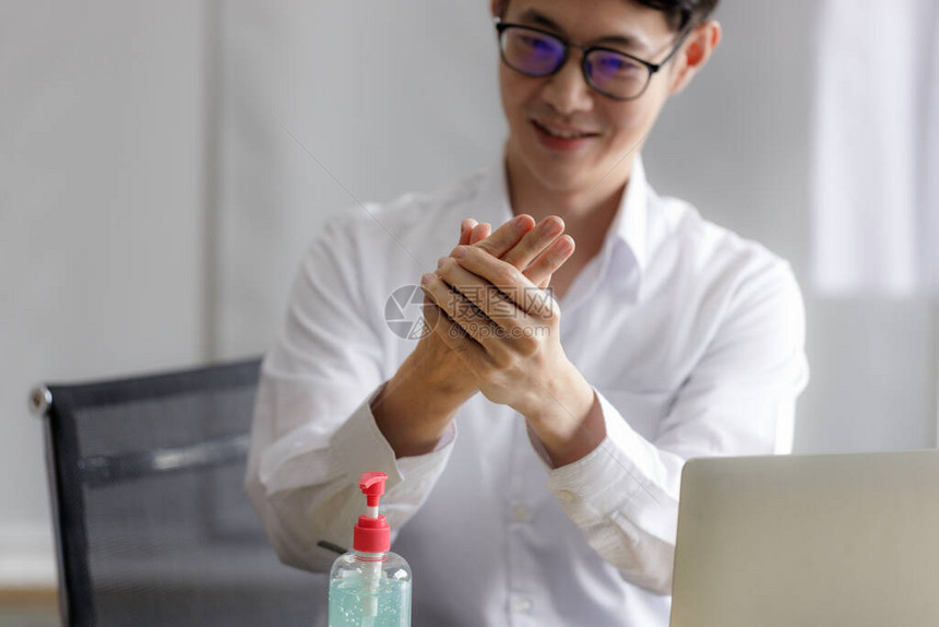 年轻的亚洲商人在办公室里用酒精凝胶洗手流行期间和COVID19流行后的新图片