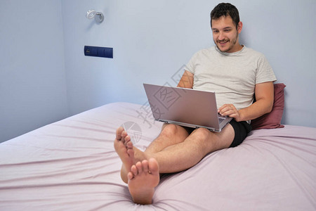 年轻成年人在床上工作打笔记本电脑从家图片