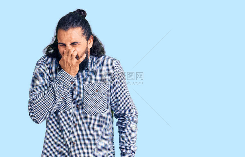 身穿散装衣的阿拉伯青年男子闻到臭味恶心难以忍受的气味图片