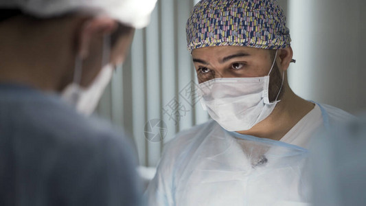 医院内的外科医生团队在进行外科手术穿着干净制服的男子在急诊手背景图片