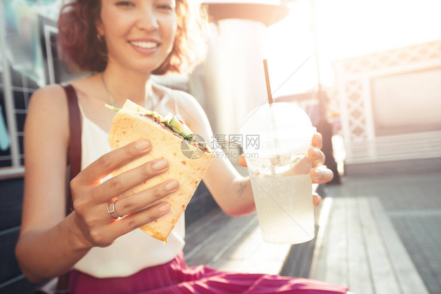 一个女人吃着美味快餐墨西哥菜饼图片