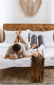 年轻的丈夫和妻子躺在床上图片