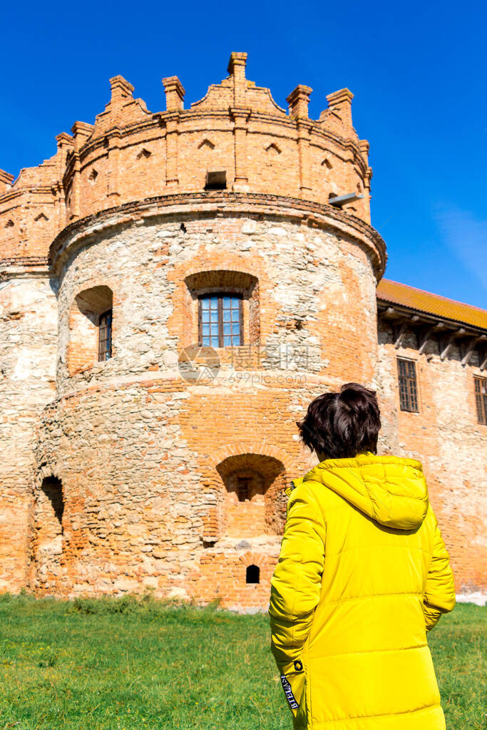 穿黄色夹克的女人在远征时望着古城的塔楼图片