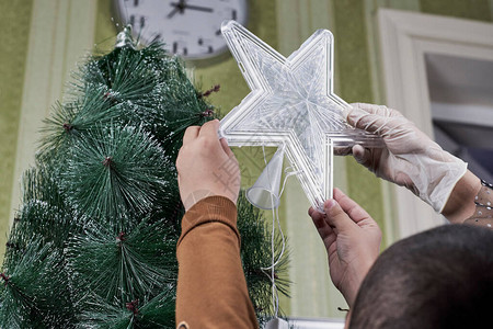 母亲帮助她儿子把星放在圣诞树顶图片
