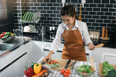 亚洲女正在厨房的平板电脑上寻找烹饪食谱网站校背景图片