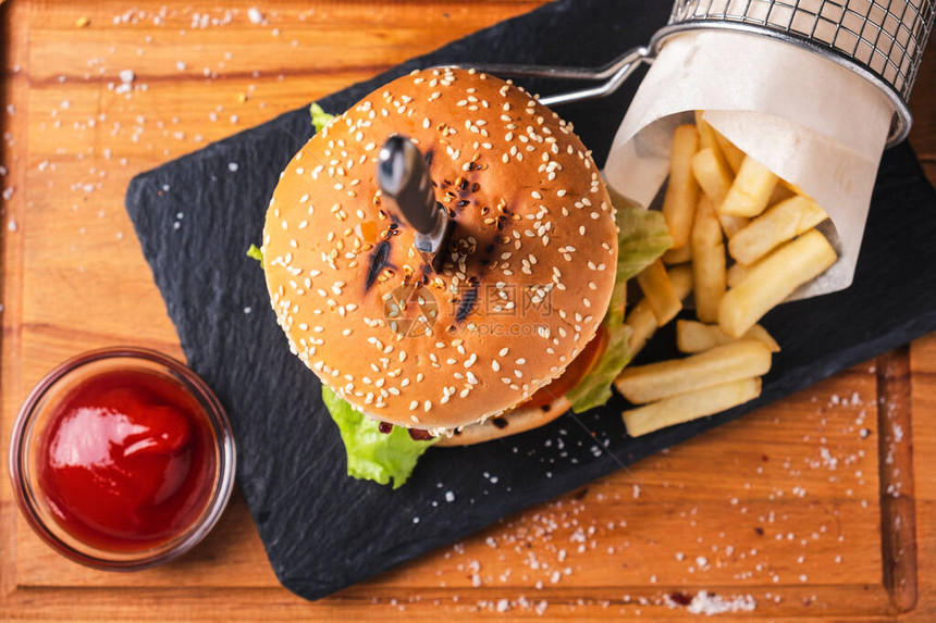 果汁牛肉汉堡加薯条和番茄酱在木板上最图片