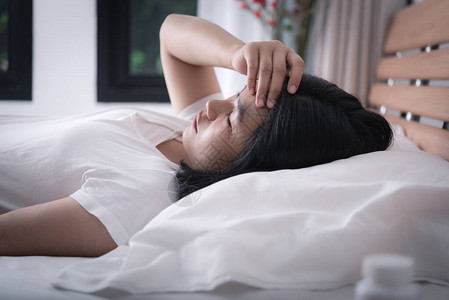亚洲女头疼感冒躺在床上图片