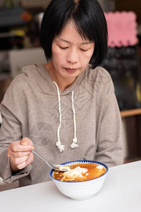 亚洲女人在商店吃豆腐布丁高清图片