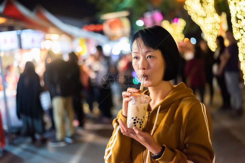 亚裔女在夜市上喝着著名的图片