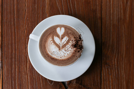 拿铁艺术热咖啡与郁金香牛奶拿铁艺术在咖啡店木桌上的白色图片